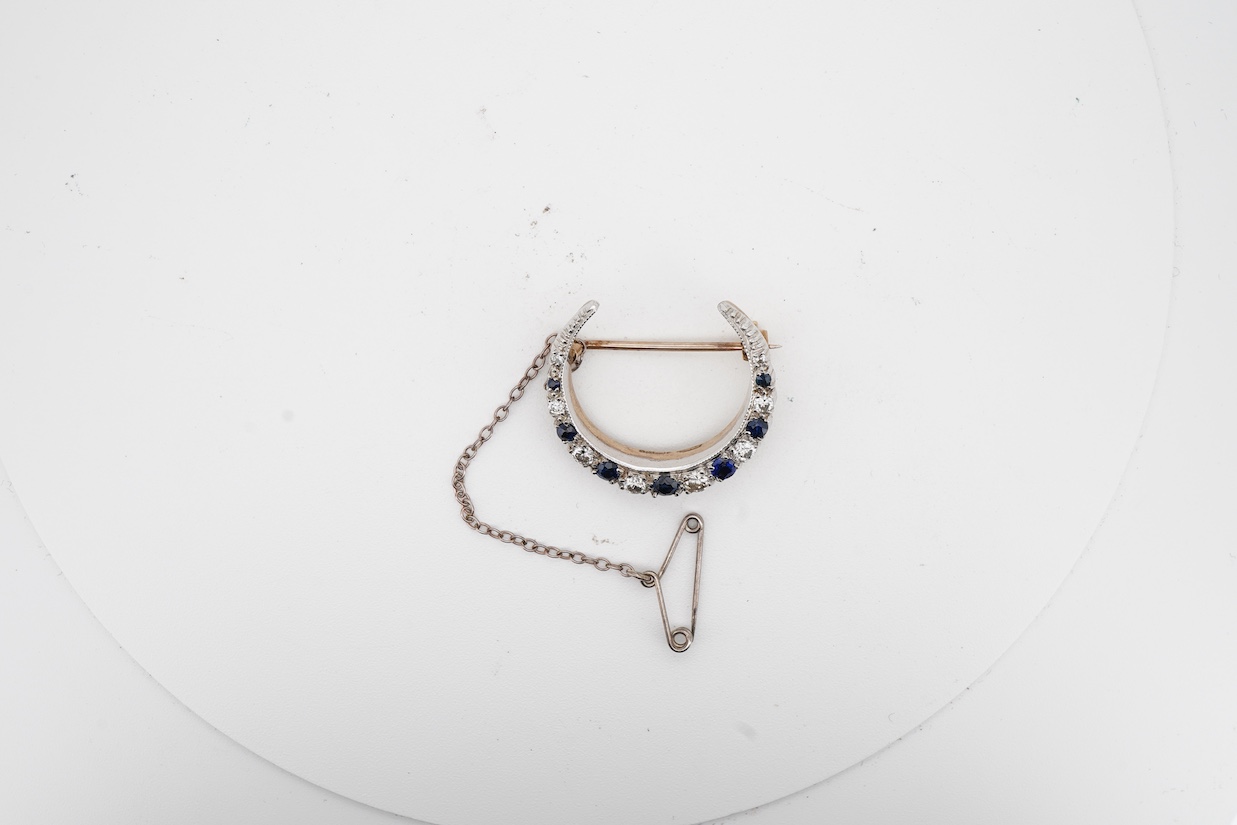 A 1970's Edwardian style 9ct gold, graduated sapphire and diamond set crescent brooch, 24mm.